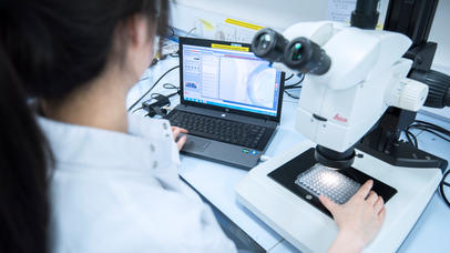 A student working with a microscope and computer.