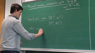 A person writing a formula on a blackboard