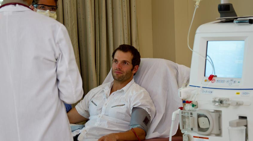 Patient in a bed in hospital with two doctors beside him