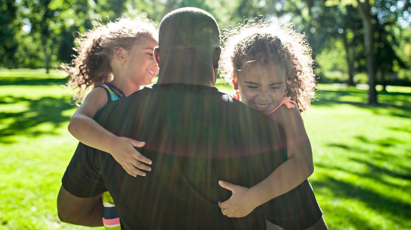 Children cuddling their dad