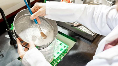 A person in a lab coat mixes a substance in a bowl, demonstrating a scientific experiment.
