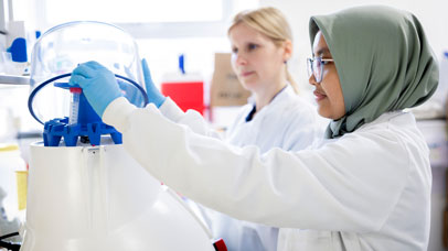 Two people working in a lab, wearing lab coats.