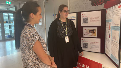 Two people standing looking at a board of posters.