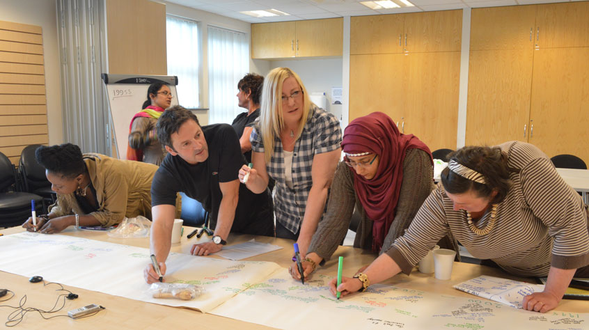 People working together on large sheets of paper on a table.