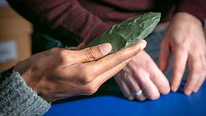 A hand holding a rare green gemstone