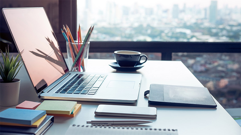View of a table with a laptop and a coffee cup overlooking a large city.