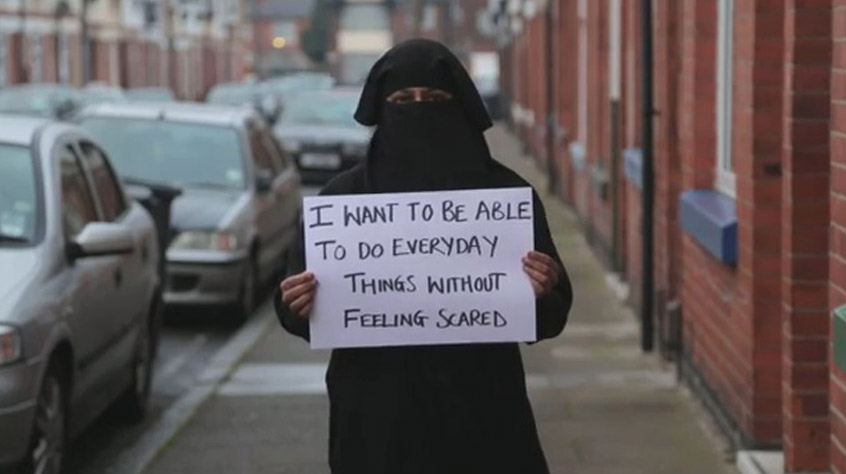 A woman in a minority group stood outside holding a sign which reads I want to be able to do everyday things without feeling scared