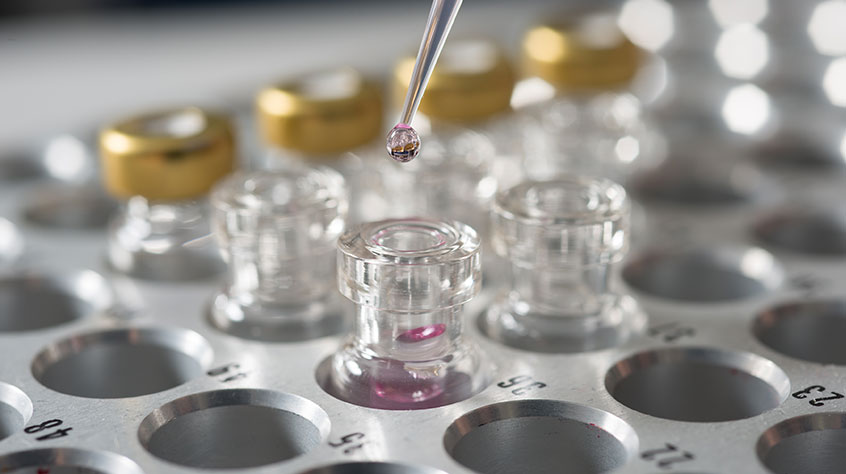 Scientific samples being dripped into a glass container