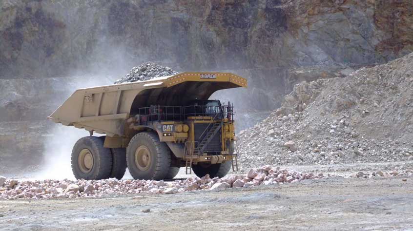Long shot of a dump truck transporting rocks at a mining site.