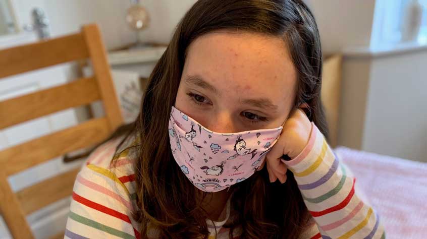 Woman sitting at table wearing a mask