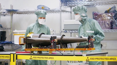 Scientists wearing full PPE and examining a piece of equipment