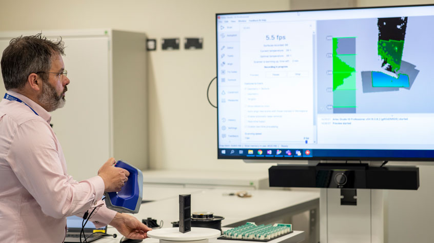 Academic standing in front of a large computer monitor