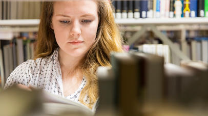A female student reads a book in the library