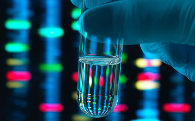 Scientist holding up a colourful test tube.