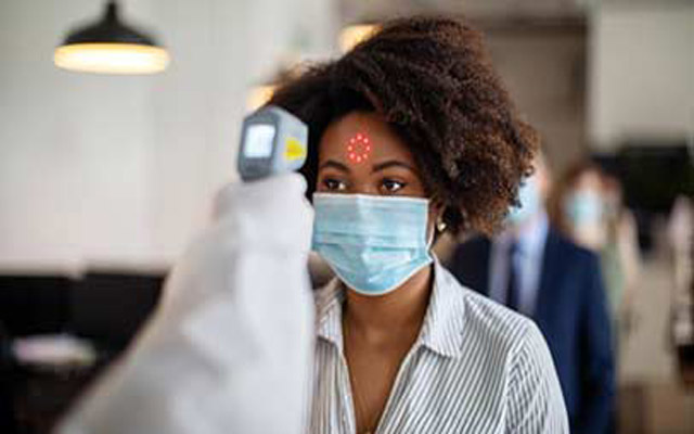lady with facemask on being checked with a sensor