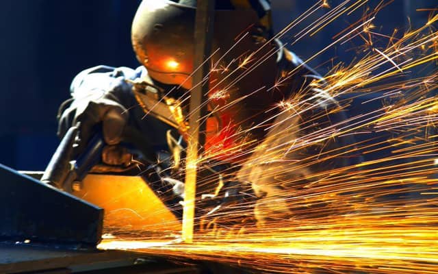 An individual welding a metal pipeline.