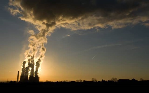 A long distance shot of factory towers, silhouetted by the setting sun.