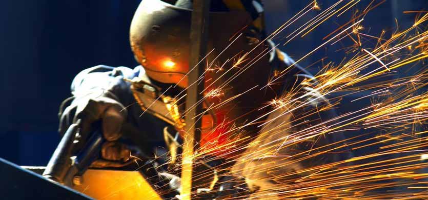 An individual welding metal for metal pipelines, producing sparks.