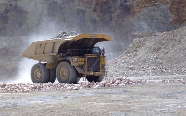 Long shot of a dump truck transporting rocks at a mining site.