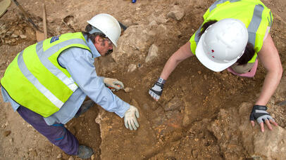 Two men in hard hats digging on location