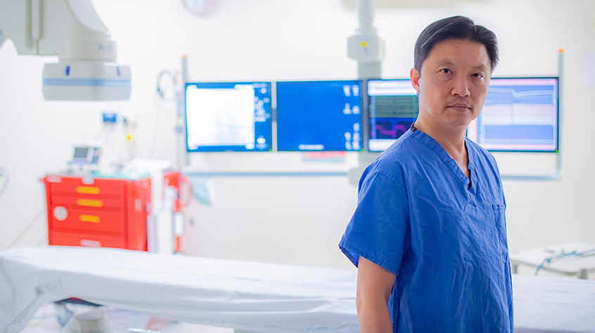 Doctor stood in a medical room in front of screens and different equipment
