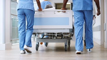 two nhs staff members are pushing a bed down a corridor inside a hospital
