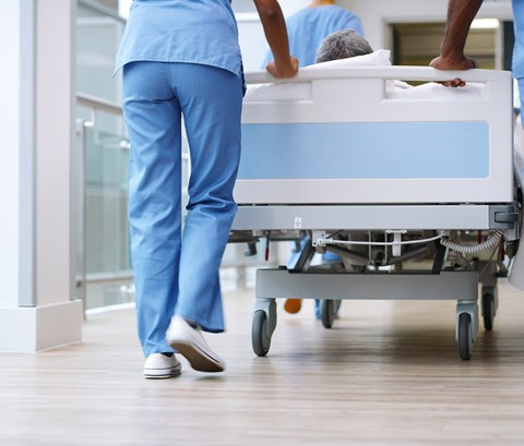 two nhs staff members are pushing a bed down a corridor inside a hospital