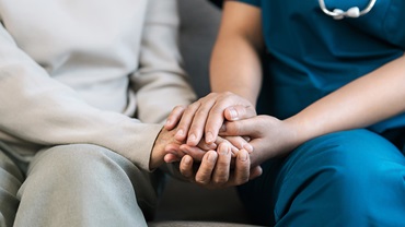 nhs staff member comforting a patient by holding their hands