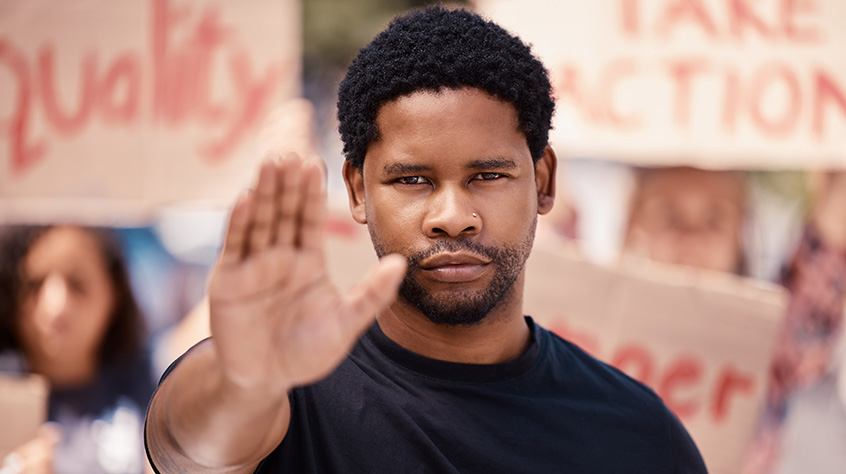 Man holding out his hand stood in front of protestors