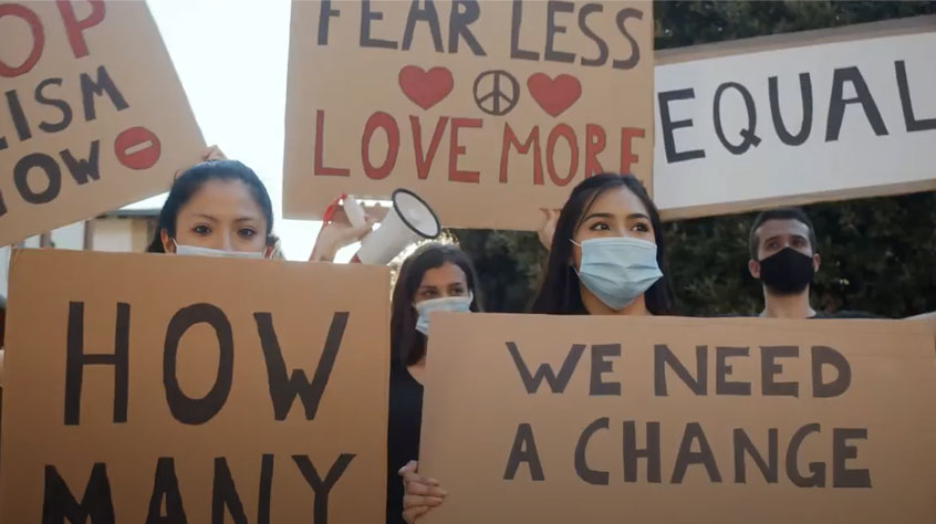 Screen capture from our promotional video highlighting social justice research. Protester stand with plaquards