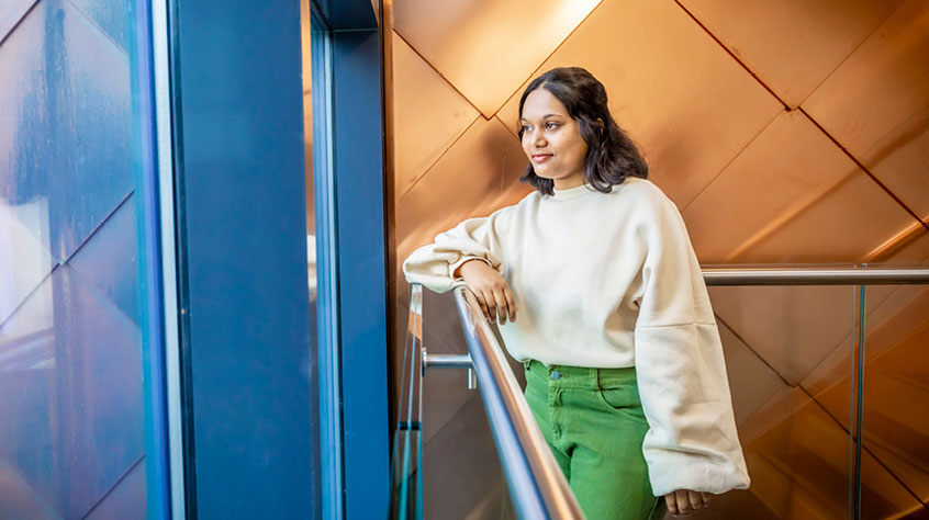 Student standing at a bannister and looking out of a window