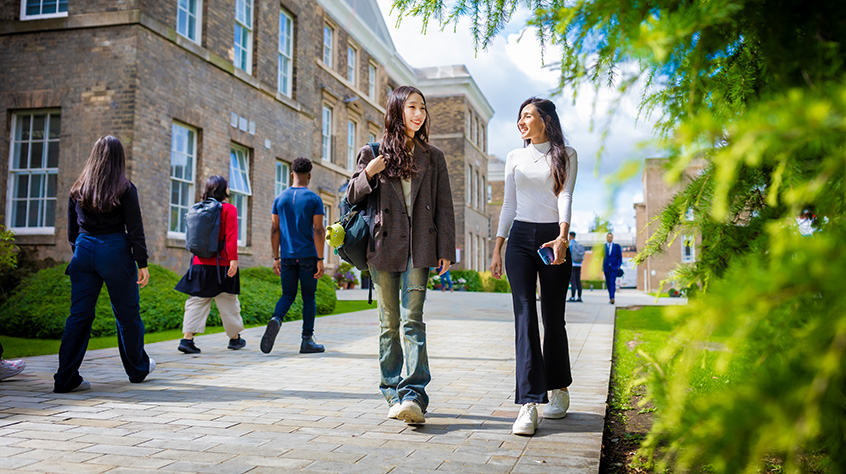 Two female students walking towards Centenary Square from Fielding Johnson which can be seen in the background