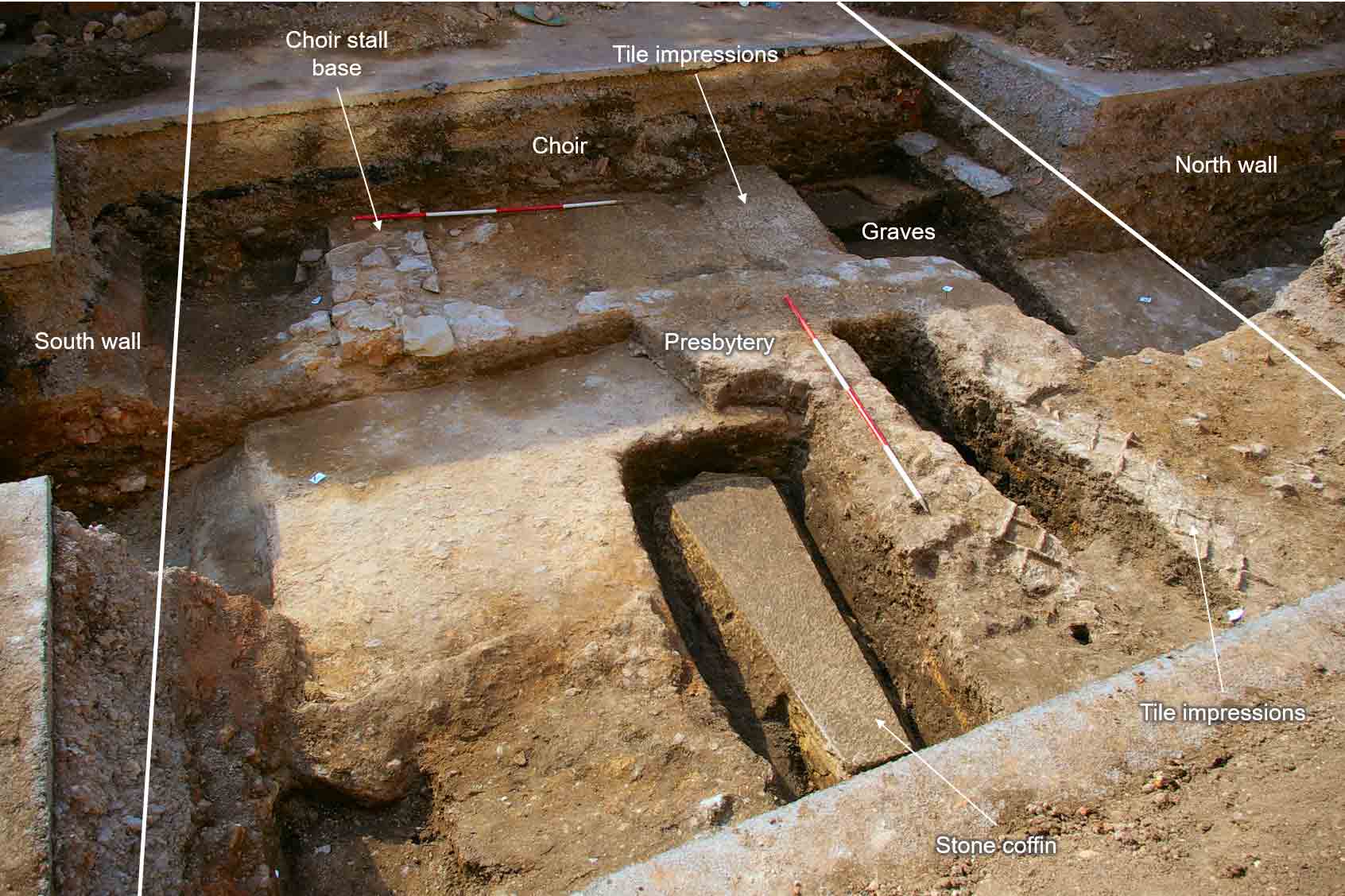 Trench 3 (G-H) fully excavated, looking west. A medieval stone coffin and tile impressions in the presbytery of the church can be seen in the foreground, with the remains of the choir stalls behind.