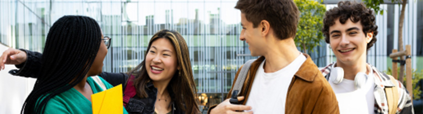 Four students speaking with each other and smiling