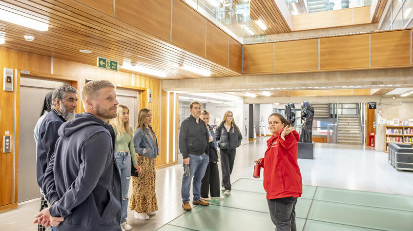 A group of people in the David Wilson Library during a campus tour lead by a student ambassador 