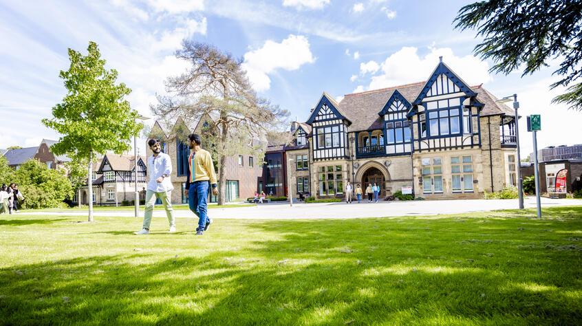 Two students walking through the gardens in front of the Brookfield School of Business