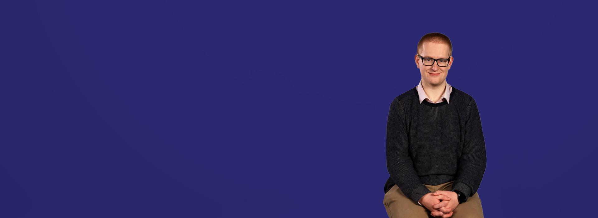 Student Charlie looking into camera with a dark blue background behind him.