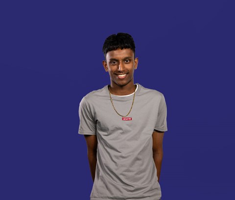 Student Jineth looking into camera with a dark blue background behind him.