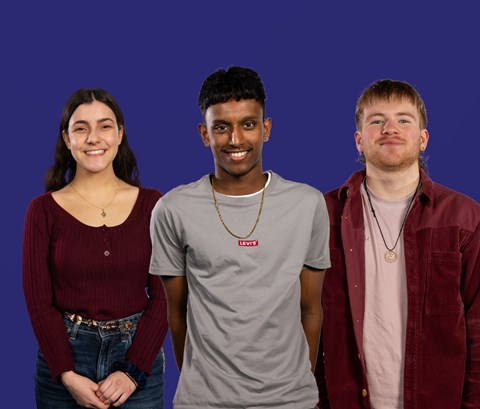 Three students looking into the camera, with a dark blue background behind them.