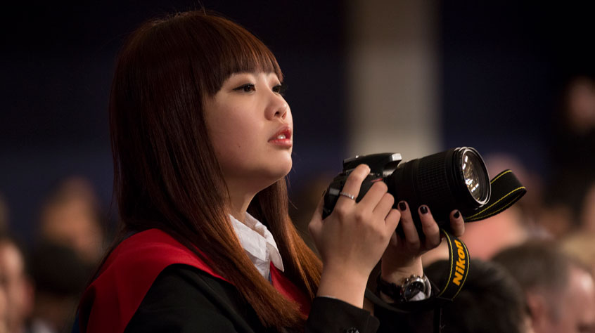 Student holding a camera at graduation.