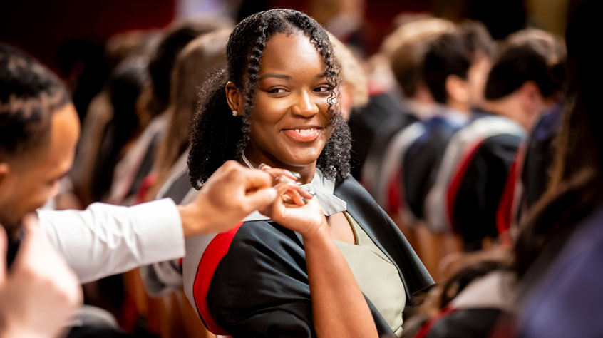 Student smiling in graduation robes.