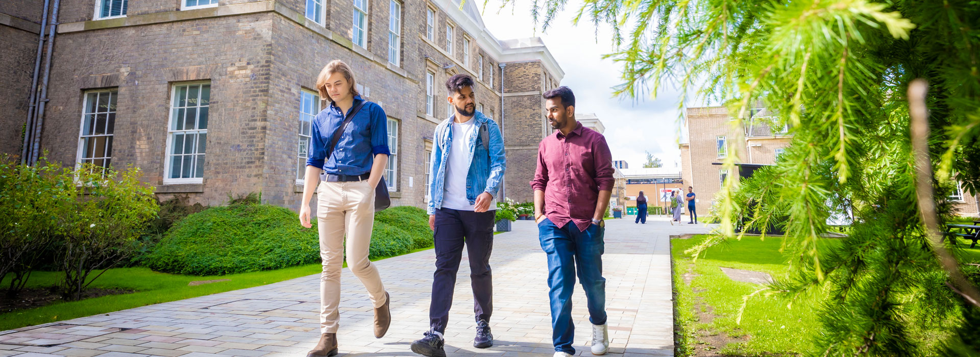Three students walking past the Fielding Johnson Building on campus.