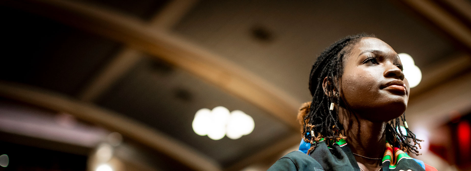Student standing up in a big hall at graduation.
