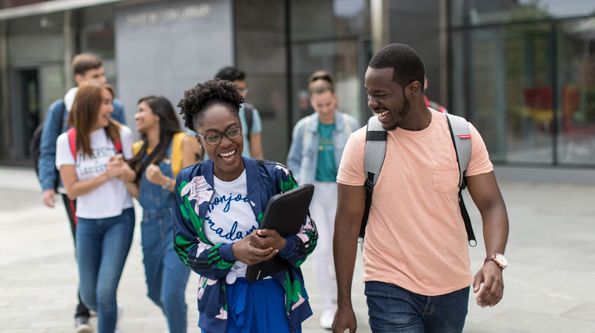Students walking together and laughing outside of the David Wilson Library.