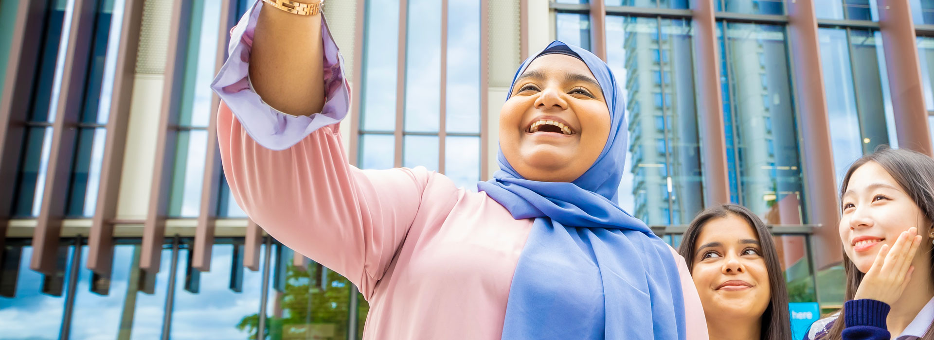 Students taking a selfie in front of the Students' Union building on Leicester campus.