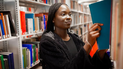 Student in the David Wilson Library, taking a book from a shelf.