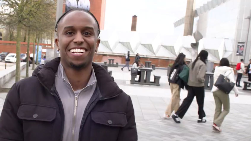 Student smiling in the middle of Centenary Square on Leicester campus,