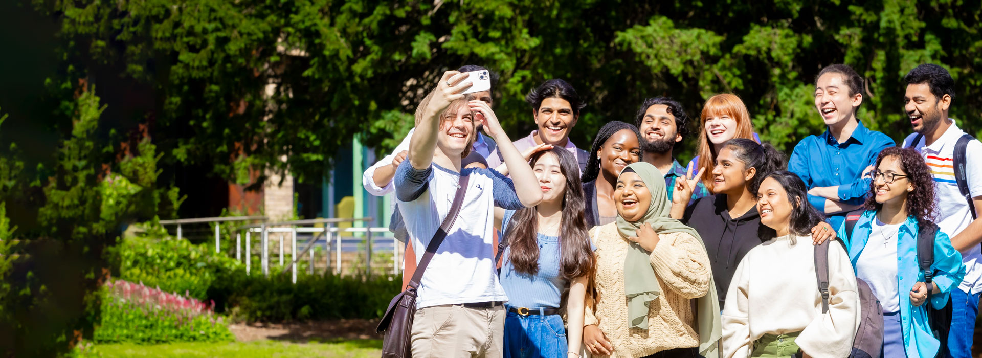Students taking a selfie in a green area on University of Leicester campus