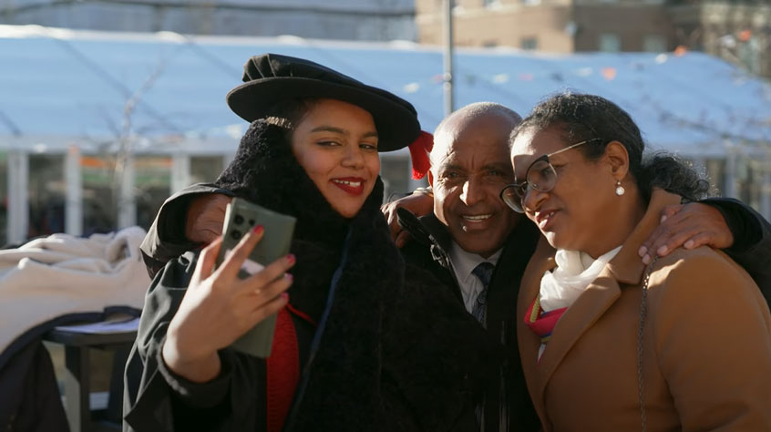 Graduating student taking a selfie with her parents outside De Montfort Hall.