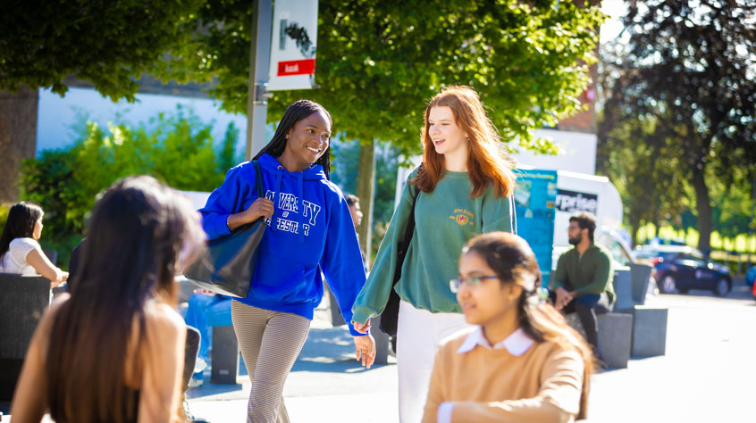 Students talking and walking through Leicester campus.